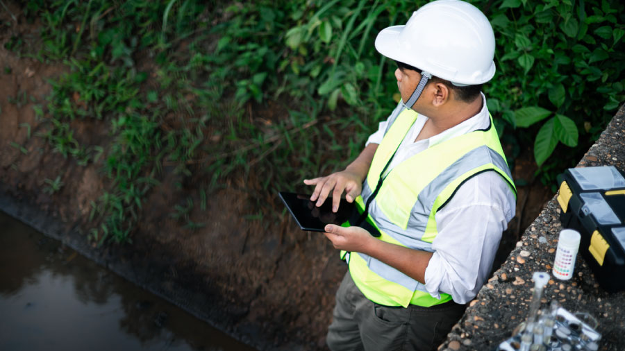Field Tech Using Tablet While Conducting Water Quality Testing By A Drainage Channel Why Environmental Data Management Breaks Down Between Field And Office Feature